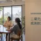明亮的室內共用空間，幾位工作者交談，右側為文章標題